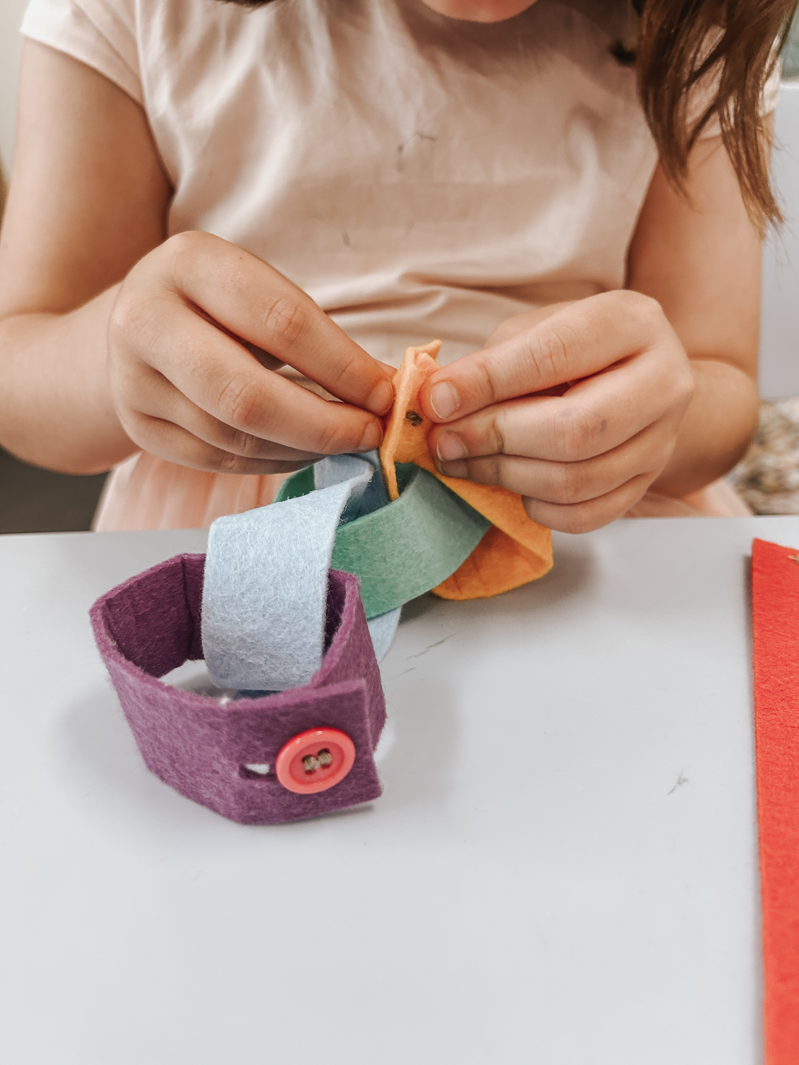 Close-up of a child threading a felt button bracelet