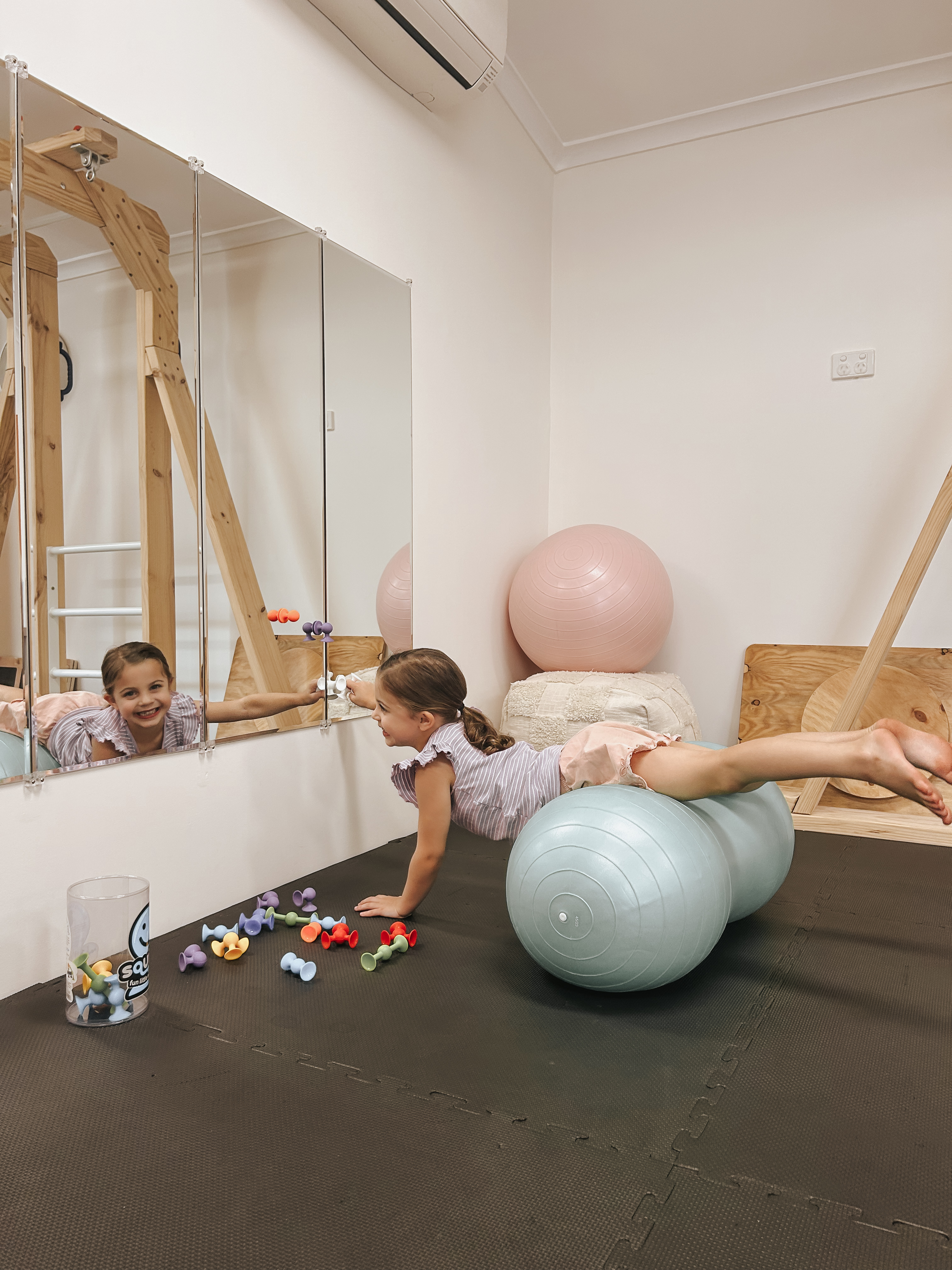 Smiling child balancing on a peanut ball in front of mirrors
